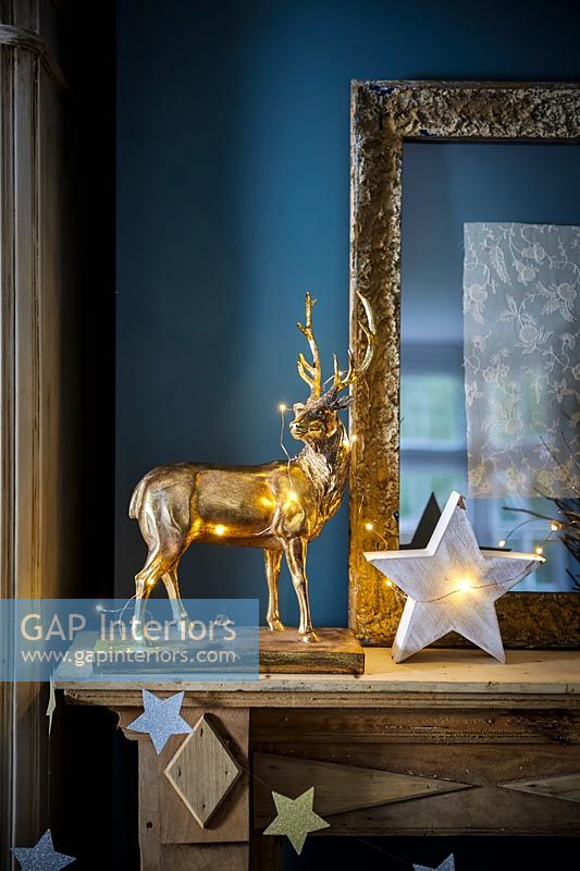 Golden stag ornament and star lights on mantelpiece 