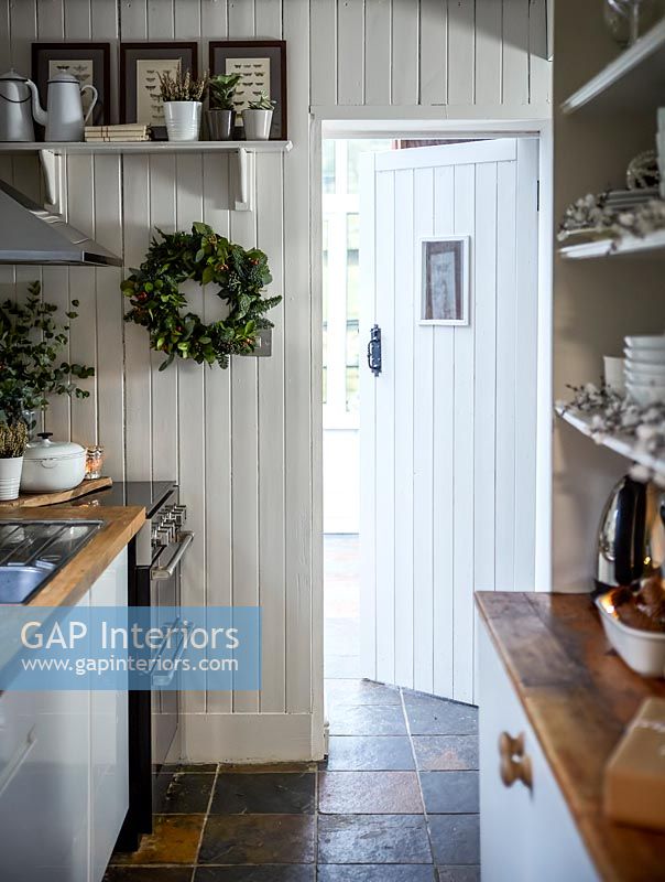Wood paneled galley kitchen with Christmas wreath on wall white 
