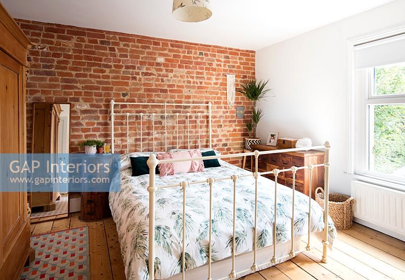 Modern bedroom with exposed brickwork and metal bed frame 