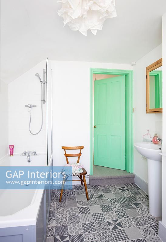 Modern bathroom with mint green painted door and patterned floor tiles 