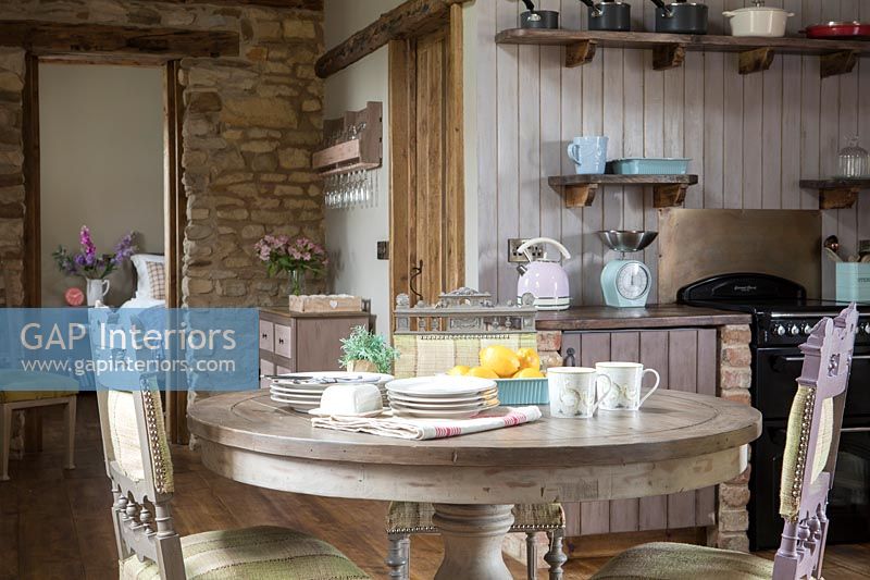 Circular table with painted chairs in country kitchen diner 