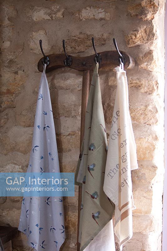 Wooden coat hanger on stone wall with variety of silk scarves 