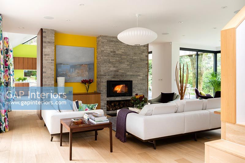 Lit fireplace in contemporary living room. Artwork by Judy McKenna