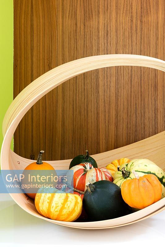 Variety of squashes and pumpkins in curved wooden basket 