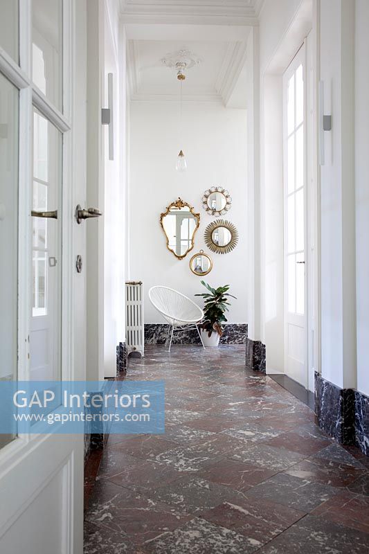 Hallway with marble floor and display of vintage mirrors 