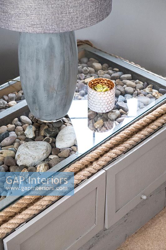 Glass top table revealing display of pebbles inside 