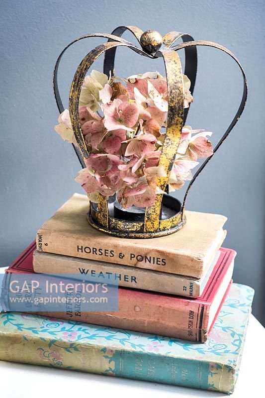 Pile of books and decorative crown and dried flowers 