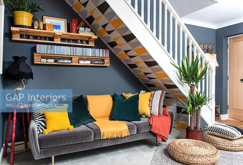 Modern living room with patterned wallpaper under stairs 