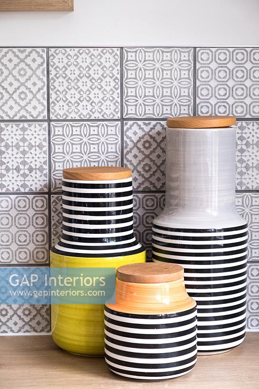 Ceramic storage jars in kitchen with patterned grey tiles 
