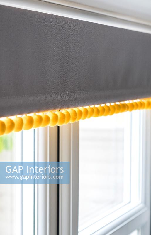 Modern grey roller blind with yellow bobbles 