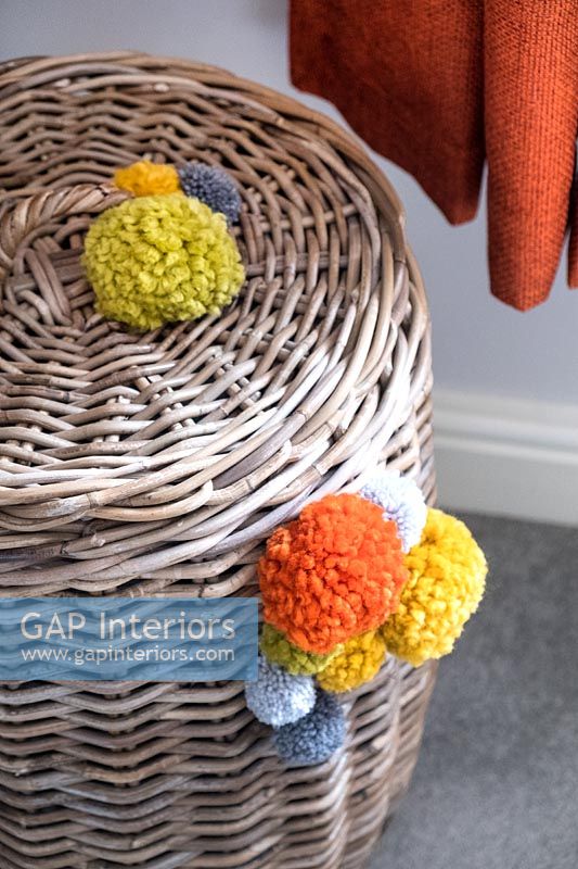 Laundry basket decorated with colourful pompoms 