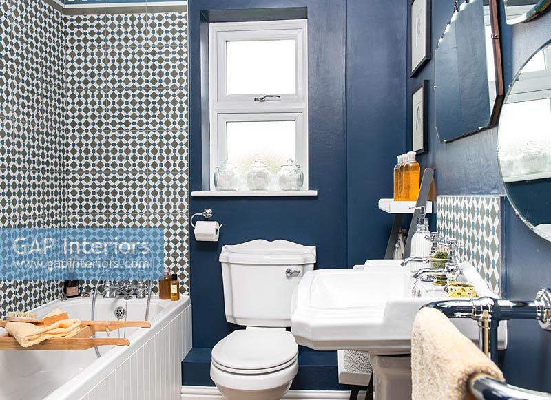 Classic bathroom with dark blue painted walls and decorative tiling 
