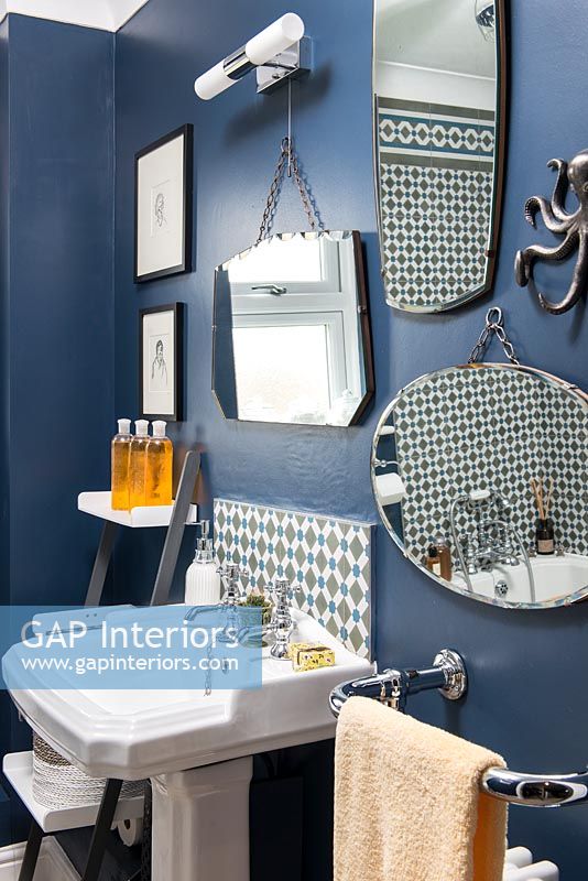Classic bathroom with dark blue painted walls and mirrors 