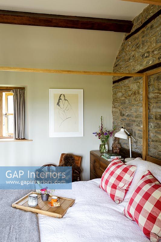 Exposed stone wall and wooden beams in country bedroom 