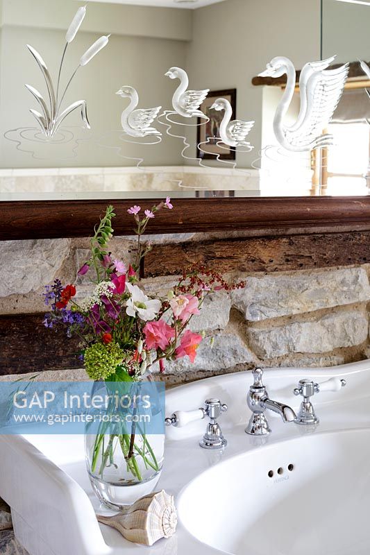 Decorative carved mirror above sink in country bathroom 