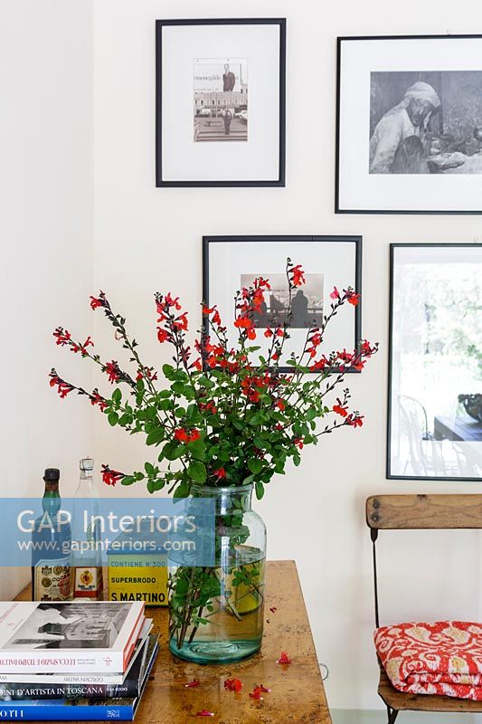 Vase of flowers on table - wall display of framed photographs 