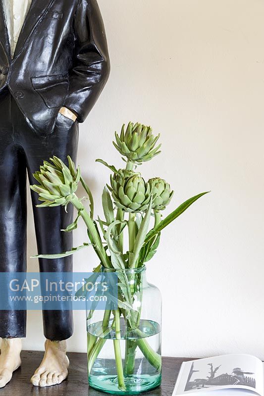 Artichokes in vase next to sculpture 