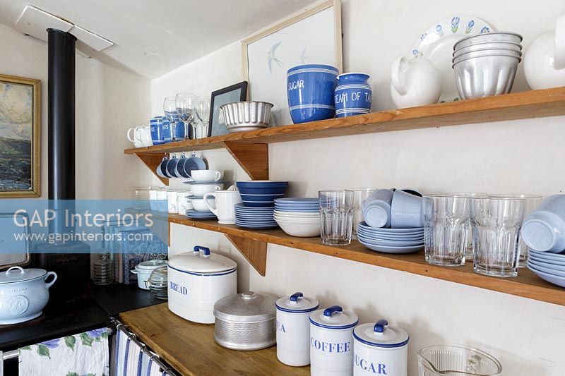 Blue and white crockery on wooden shelf in cottage kitchen 