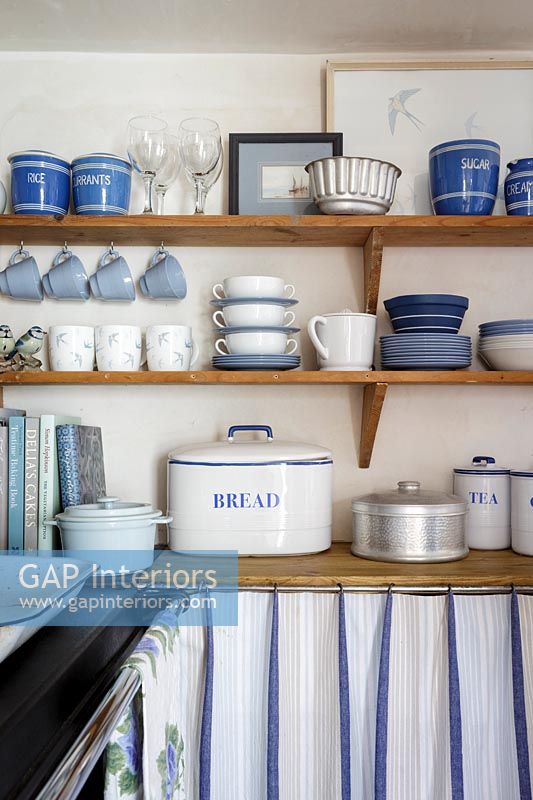 Blue and white crockery on wooden shelf in cottage kitchen
