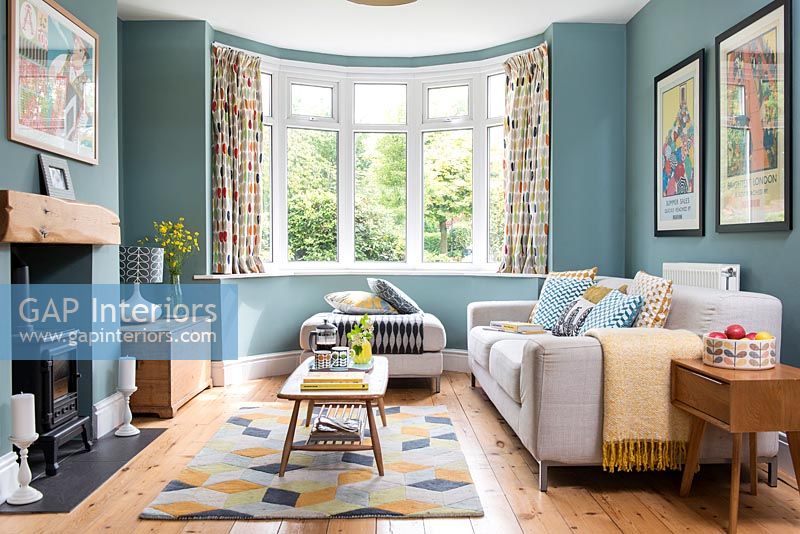 Modern living room with large bay window and teal painted walls 