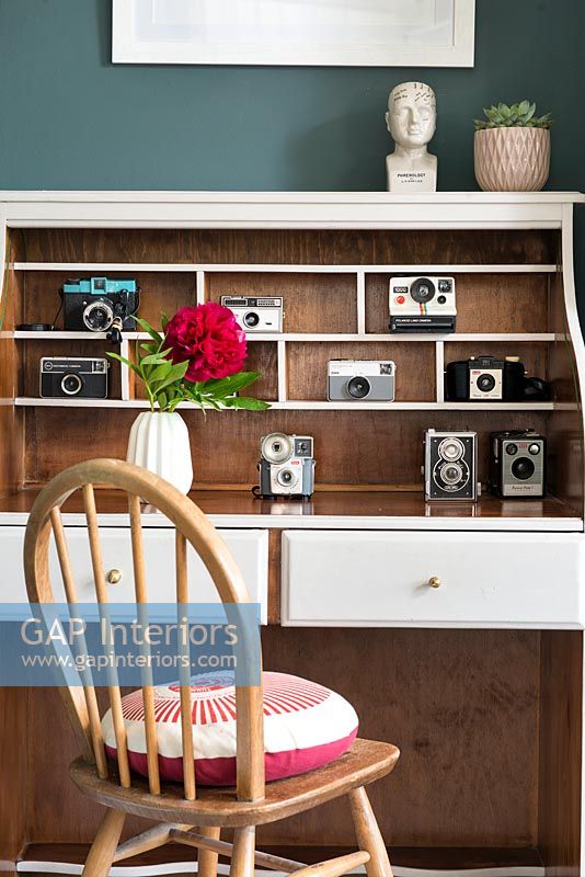 Display of vintage cameras in white bureau shelves 