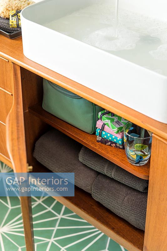 Towels and accessories in vintage sideboard under sink 