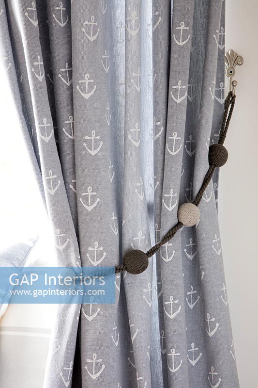 Curtains with anchor motif tied back with decorative rope