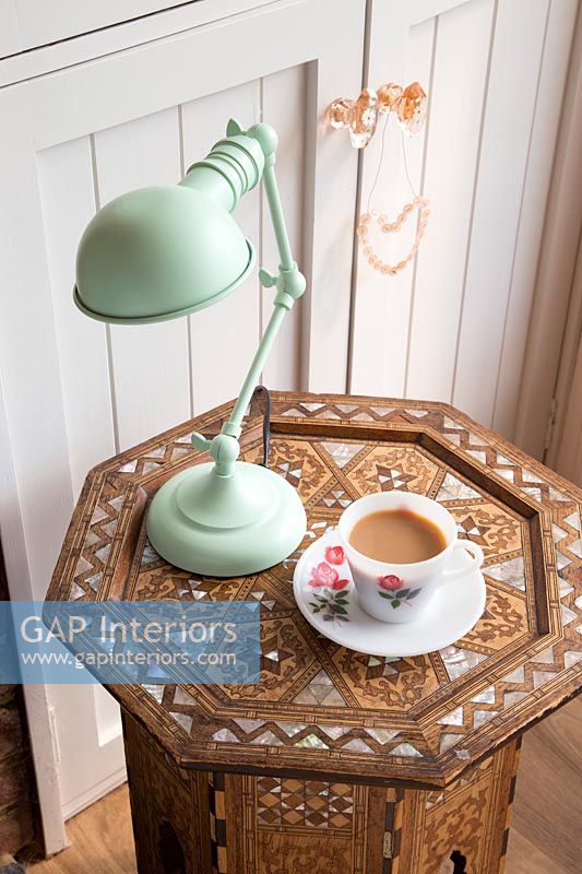 Green lamp and cup of tea on decorative wooden table 