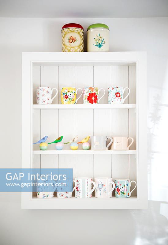 Painted white shelf unit with colourful mugs and ornaments 