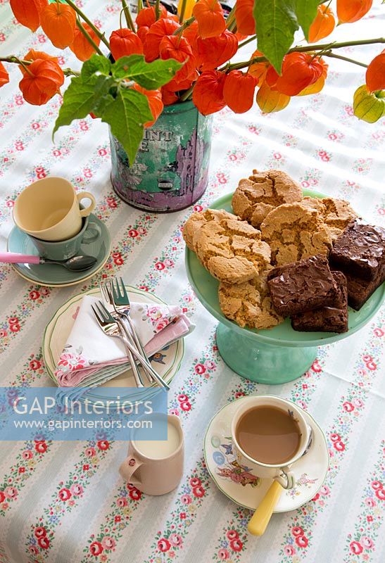 Tea and biscuits on dining table with vintage patterned table