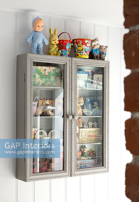 Wall mounted glass cabinet filled with vintage items 
