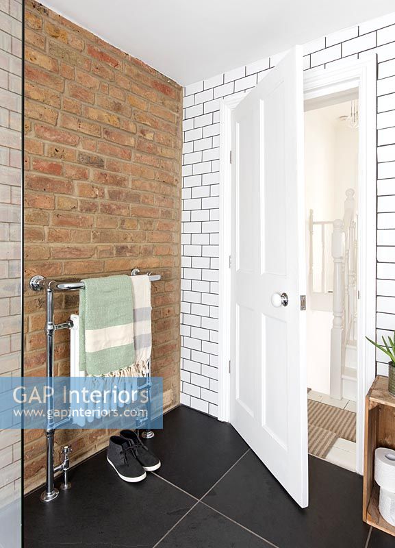 Exposed brick wall and brick style white tiling in modern bathroom 