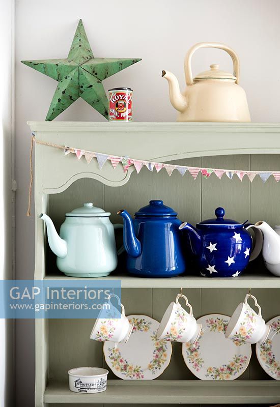 Collection of teapots and crockery on painted green wooden dresser 