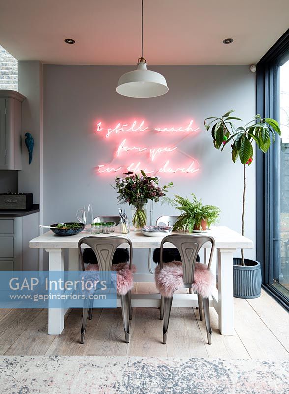 Pink neon light on feature wall above dining table 