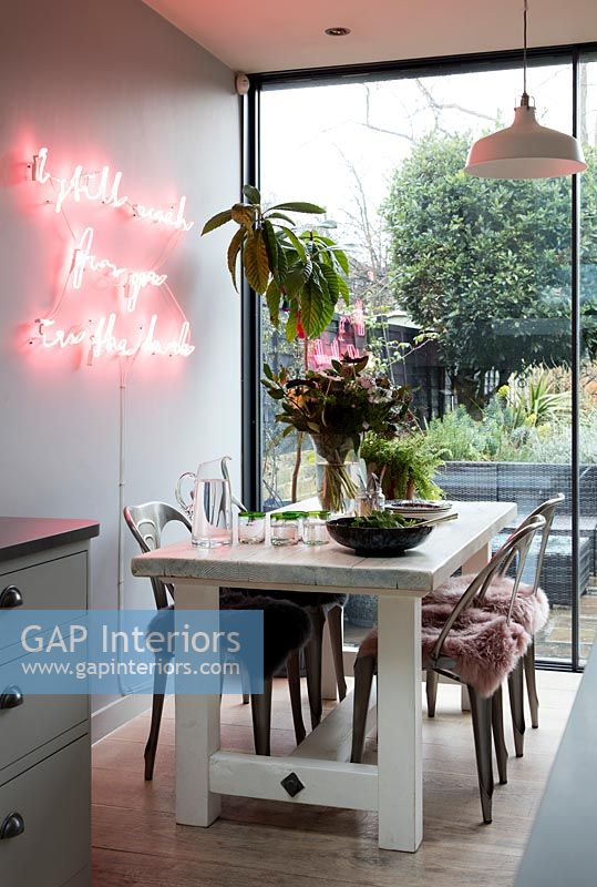 Illuminated pink neon artwork on feature wall of contemporary dining room 