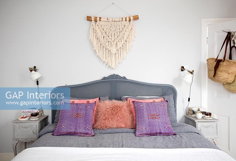 Upholstered grey headboard and cushions on bed 