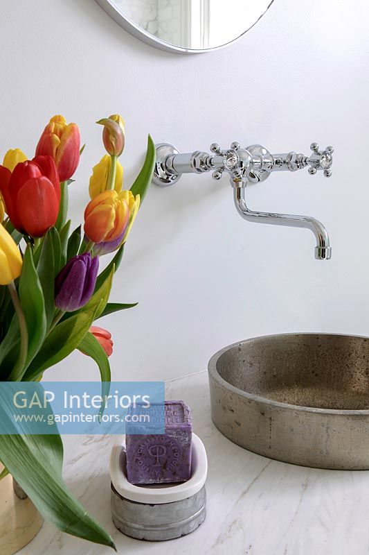 Colorful tulips next to round metal sink 