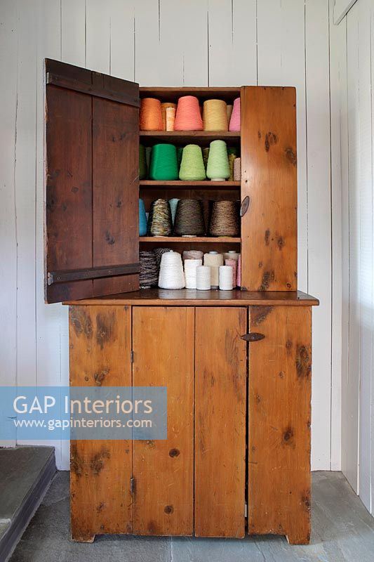 Vintage wooden cabinet filled with colourful spools of thread 