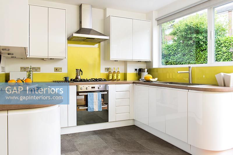 Modern white kitchen with yellow perspex splash backs 