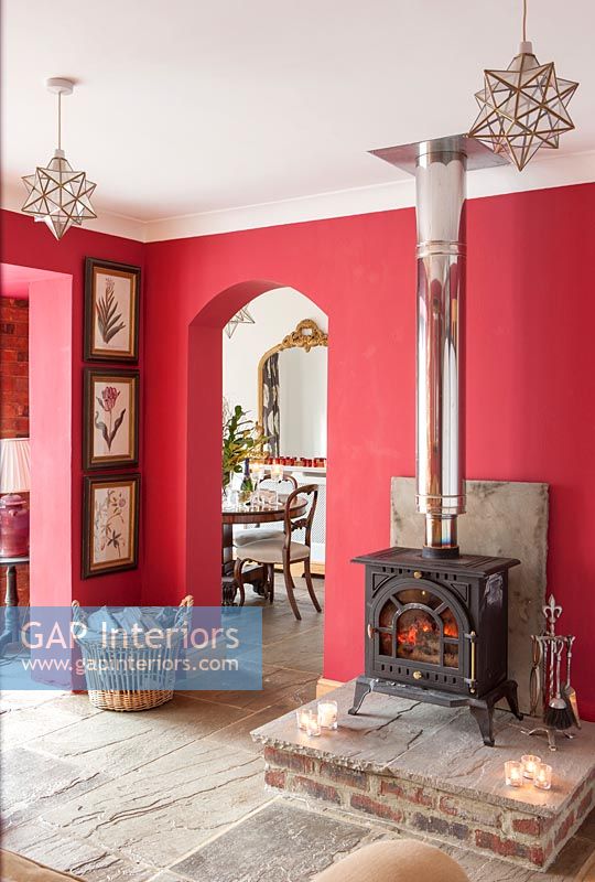 Wood burning stove in country living room with red painted walls at Christmas 