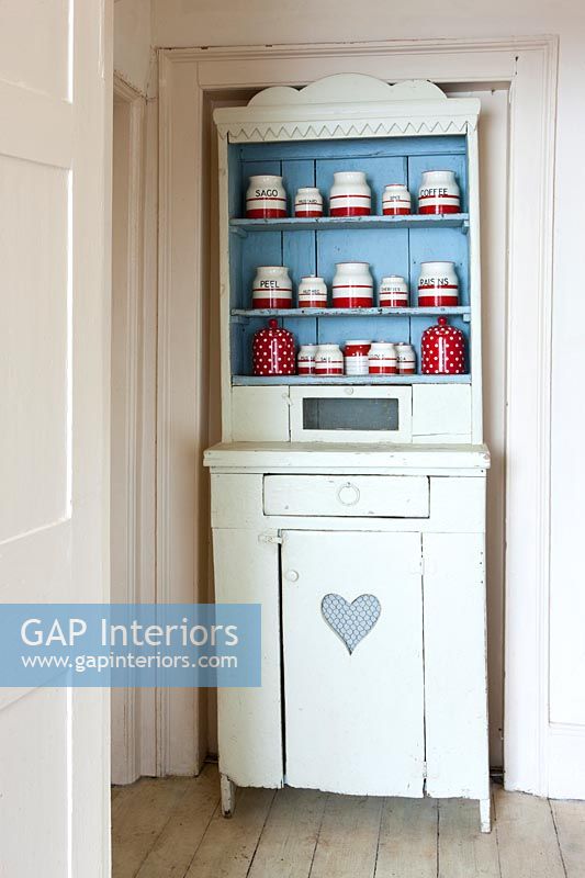 Painted vintage dresser with display of red and white storage jars 