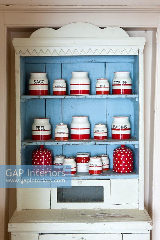 Display of red and white storage jars on painted dresser 