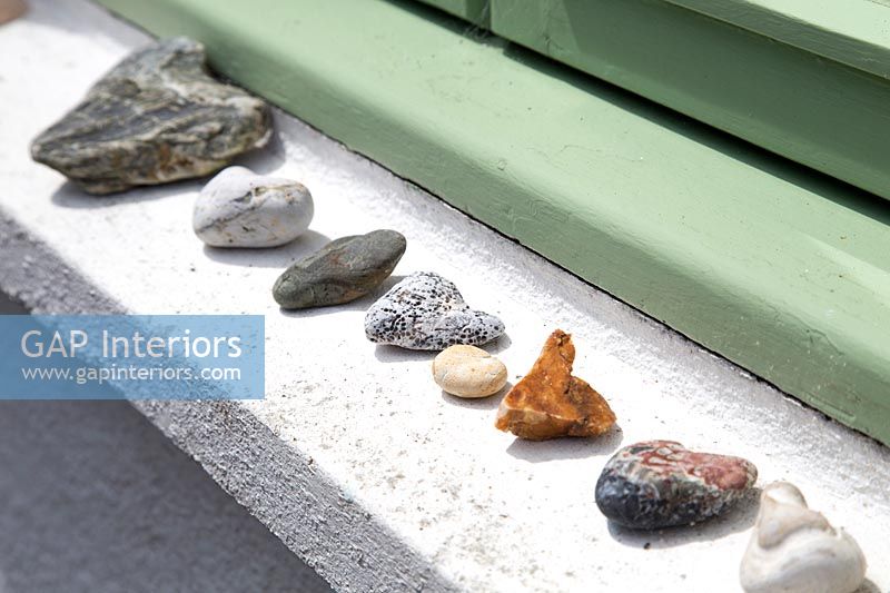 Row of pebbles and stones on exterior windowsill 