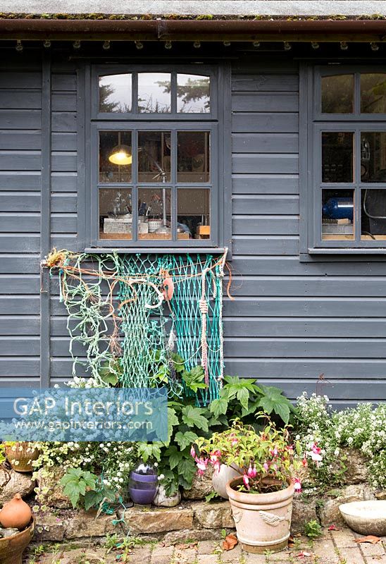 Fishing net suspended from windowsill of grey painted timber clad house 