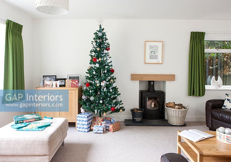 Christmas tree next to fireplace in modern living room 
