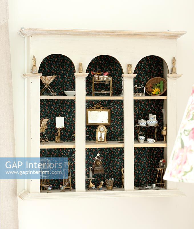 Miniature furniture in alcove shelves with fabric backdrop