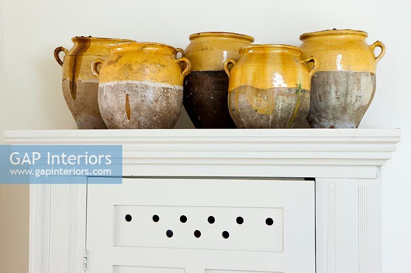 Collection of ceramic pots on top of cabinet 
