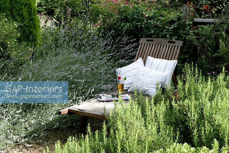 Wooden recliner with cushions in herb garden 