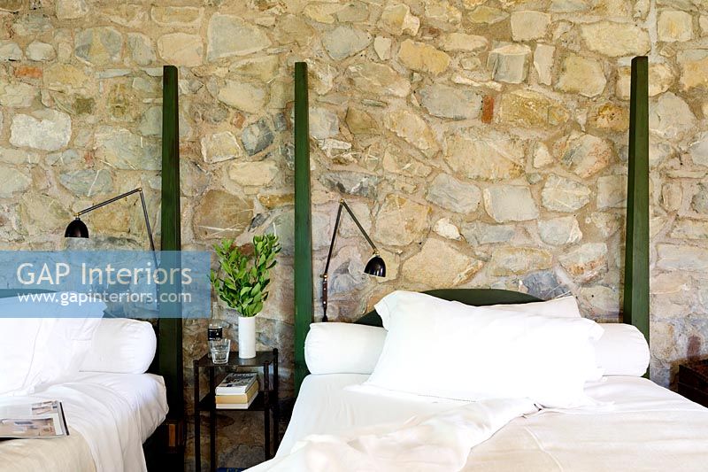 Twin beds and exposed stone wall in modern country bedroom 