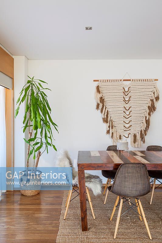 Modern dining room with fabric wall hanging and large houseplant 